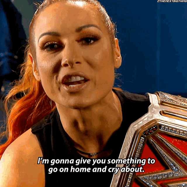 a woman is holding a wrestling championship belt and says i 'm gonna give you something to go on home and cry about