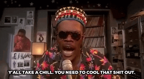 a man wearing a hat and sunglasses is talking into a microphone .
