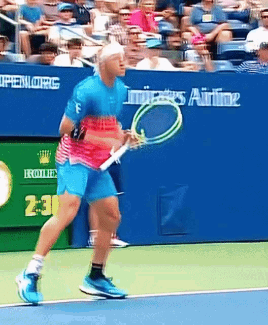 a man playing tennis on a court with a rolex ad behind him