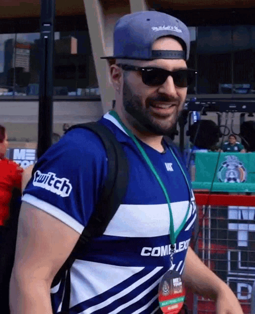 a man wearing sunglasses and a twitch shirt smiles