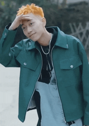 a man with orange hair is wearing a green jacket and a black hoodie