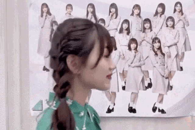 a woman in a green dress is standing in front of a group of girls .