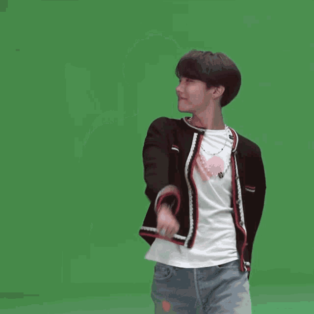 a man wearing a black jacket and a white t-shirt is standing in front of a green screen .