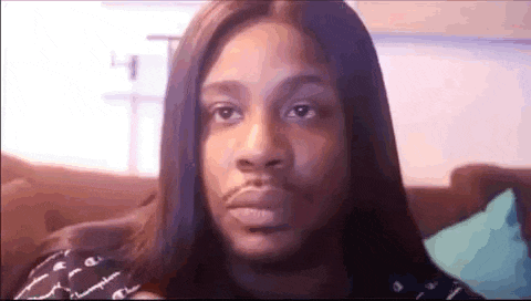 a man with long hair is sitting on a couch and looking at the camera .