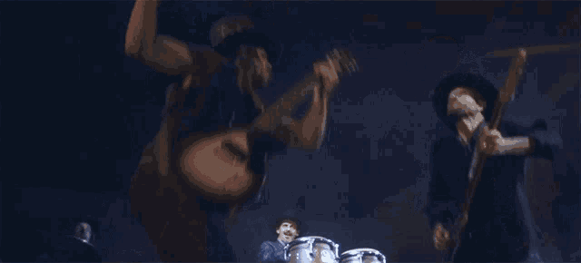a man in a cowboy hat is playing a guitar while another man plays drums