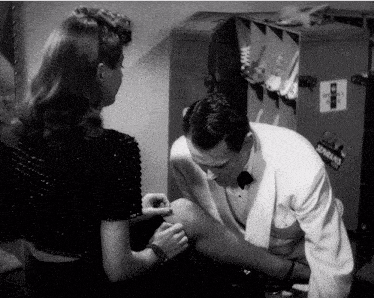a black and white photo of a man putting a bandage on a womans leg