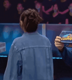 a man in a denim jacket is holding a piece of paper that says ' a ' on it