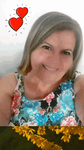 a woman in a floral top smiles with two hearts above her head