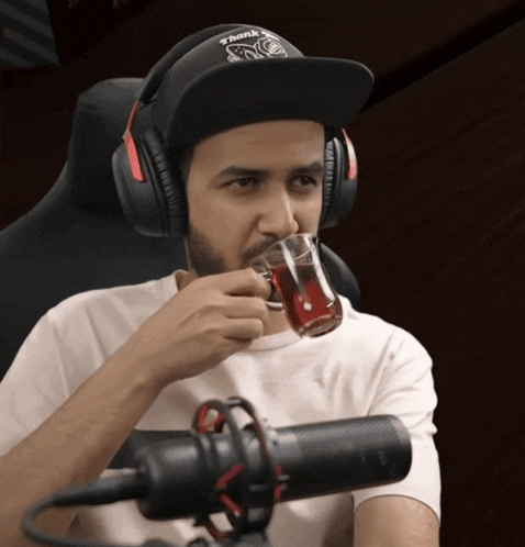 a man wearing headphones and a hat that says think twice drinks from a cup