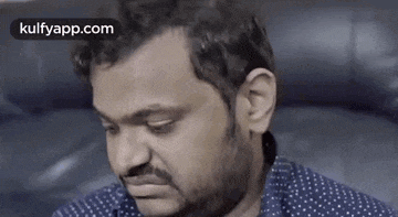 a man with a beard is sitting on a couch and making a face .