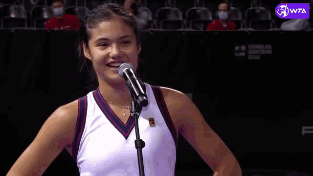 a woman is singing into a microphone while wearing a nike tank top .