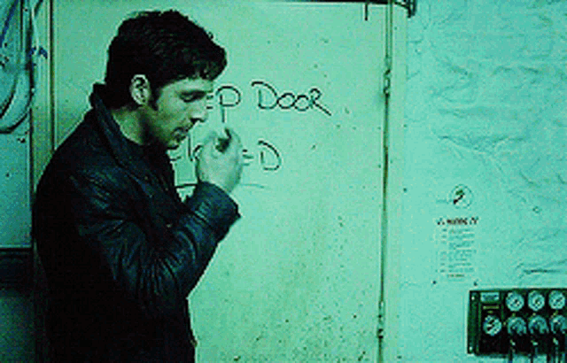 a man smoking a cigarette in front of a door that says " keep door locked "