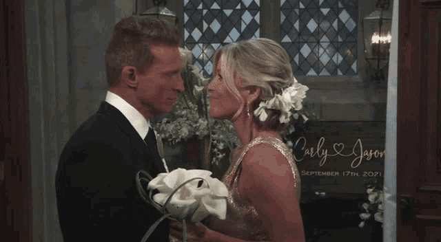 a bride and groom kissing in front of a sign that says jason