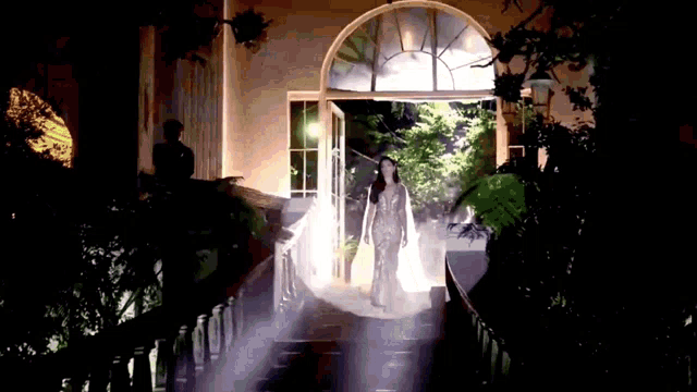 a woman in a long white dress is walking down stairs