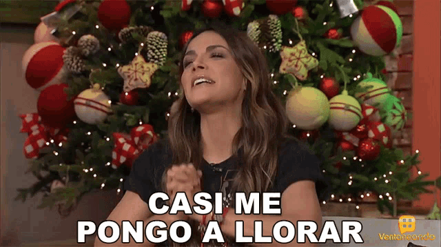 a woman sitting in front of a christmas tree with the words casi me pongo a llorar