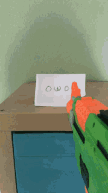 a nerf gun is pointed at a sign that says owo on it