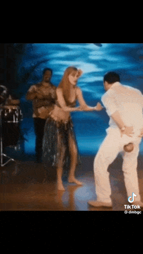 a man and a woman are dancing on a stage with a band behind them .