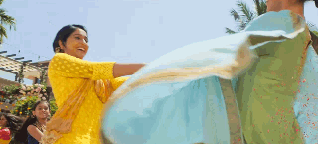 a woman in a yellow top is holding a blue cloth