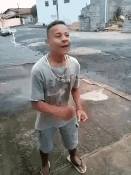 a young man is standing on the sidewalk wearing flip flops .