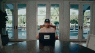 a man is sitting at a table using a laptop computer in a living room .