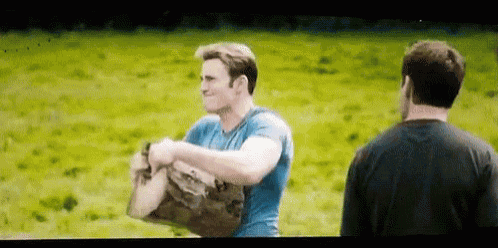 a man in a blue shirt is carrying a bag in a field while another man watches .