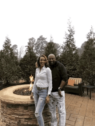 a man and a woman are posing in front of a fire pit