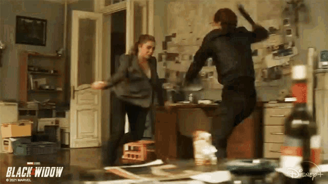 two women are fighting in a living room with a bottle of wine on the floor .