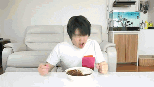 a man is sitting at a table eating a bowl of curry