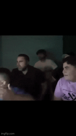 a group of people are sitting in a dark room watching a movie .