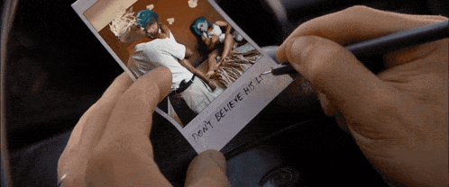 a person is writing on a polaroid with the words " don 't believe his lie "
