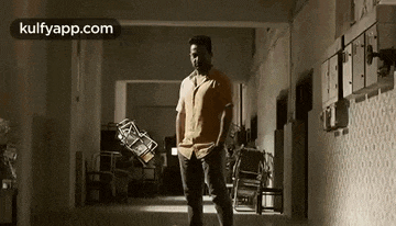 a man is walking down a hallway holding a chair in his hands .