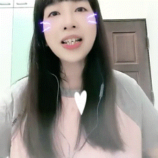 a woman wearing headphones and a pink shirt has a heart shaped necklace around her neck