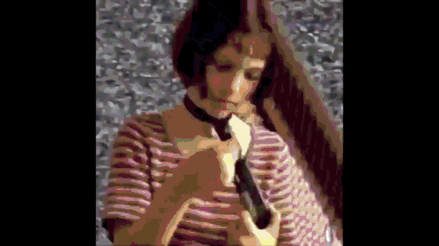 a woman in a striped shirt and tie holds a gun