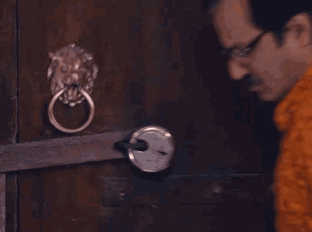 a man with a mustache and glasses is standing in front of a door .