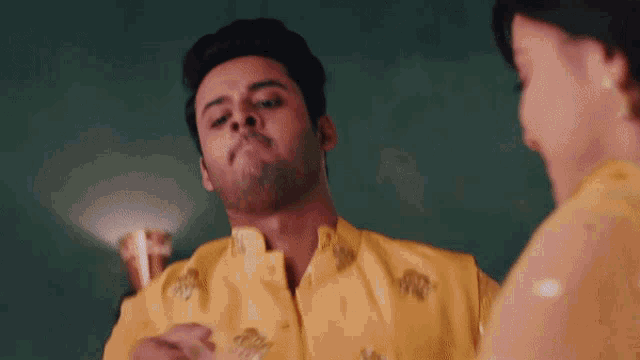a man in a yellow shirt is being sprayed by a woman