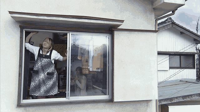 a woman in a leopard print apron is looking out of a window