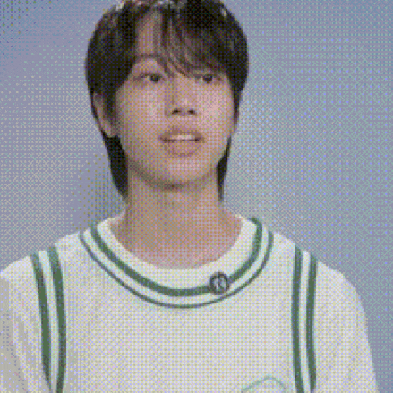 a young man wearing a white and green striped shirt is standing in front of a blue wall .