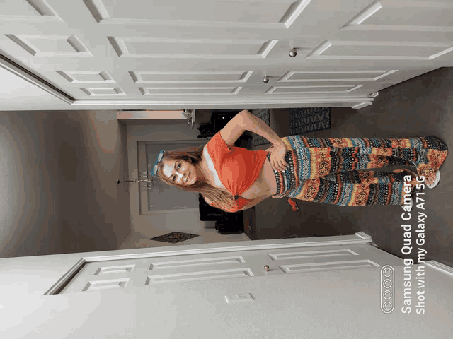 a woman standing in a hallway with a samsung quad camera shot on her phone