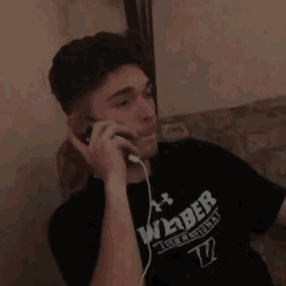 a man wearing a shirt with the number 77 on it talks on a cell phone
