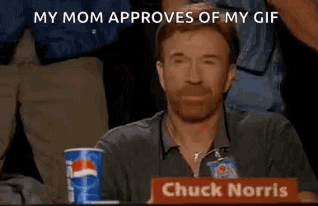chuck norris is sitting at a table with a sign that says `` my mom approves of my gif ''