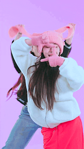 a woman wearing a pink hat and gloves covering her eyes