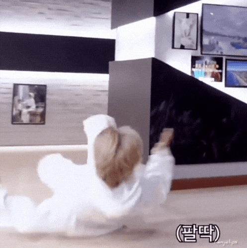 a person in a white hoodie is laying on the floor in a room