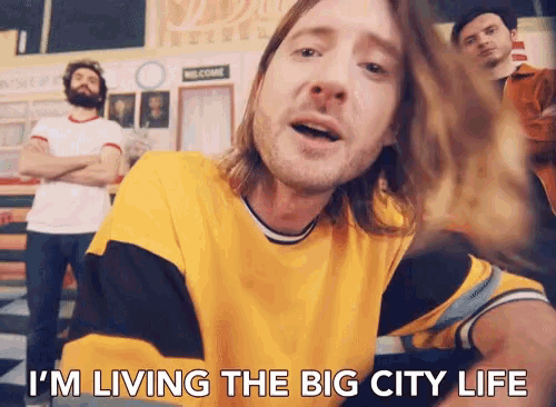 a man in a yellow shirt with the words " i 'm living the big city life " below him