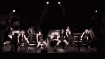 a group of people are standing on a stage in the dark .