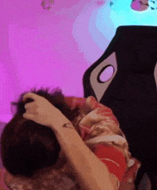 a person with a tattoo on their arm is laying on a bed with their head in their hands .