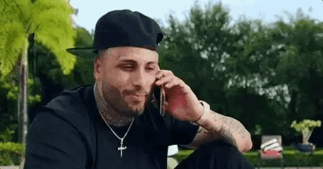 a man in a baseball cap is talking on a cell phone .