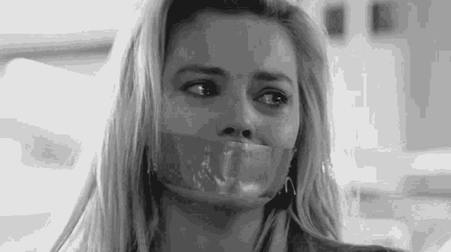 a woman with duct tape on her mouth is looking at the camera in a black and white photo .