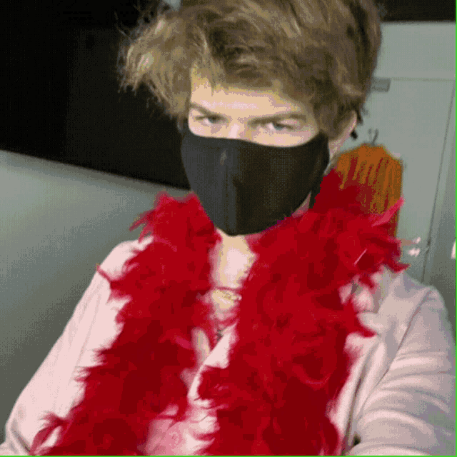 a man wearing a black face mask and a red boa around his neck