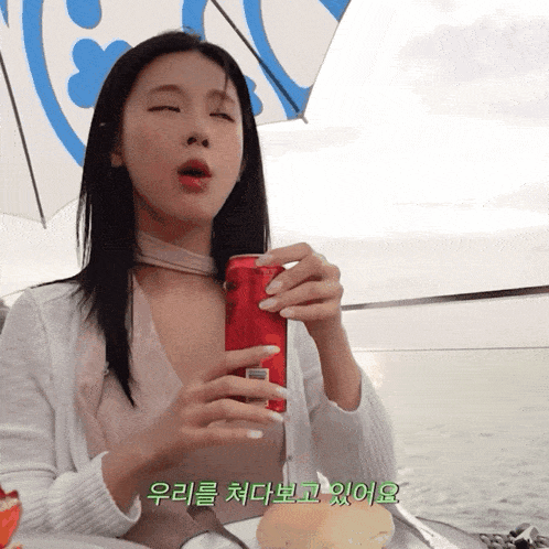 a woman drinking from a red can with foreign writing on the bottom