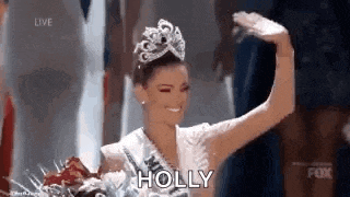 a woman wearing a tiara and a crown is standing on a stage .